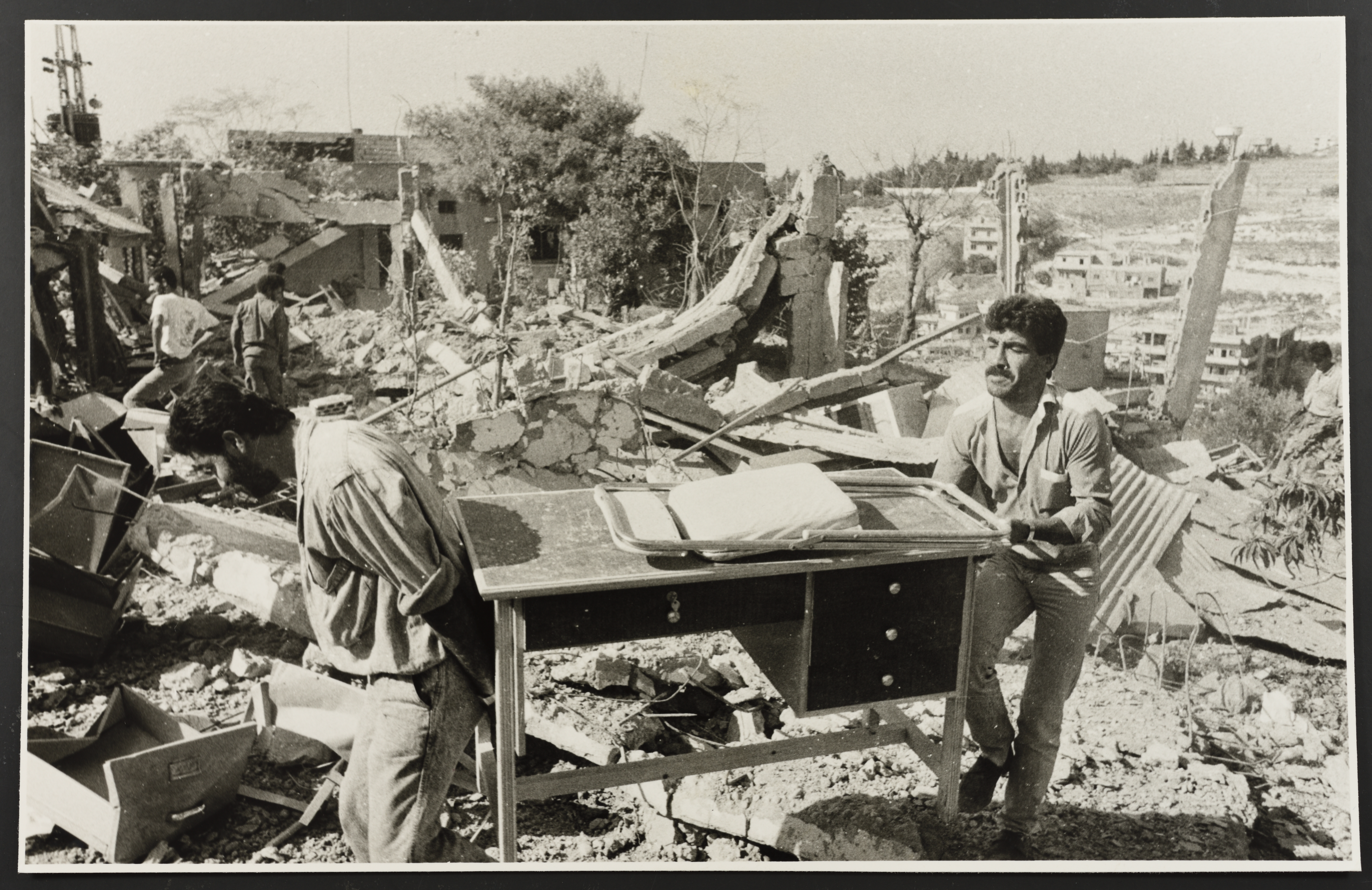 Two men carry a desk found in the rubble after an Israeli airstrike in Lebanon.